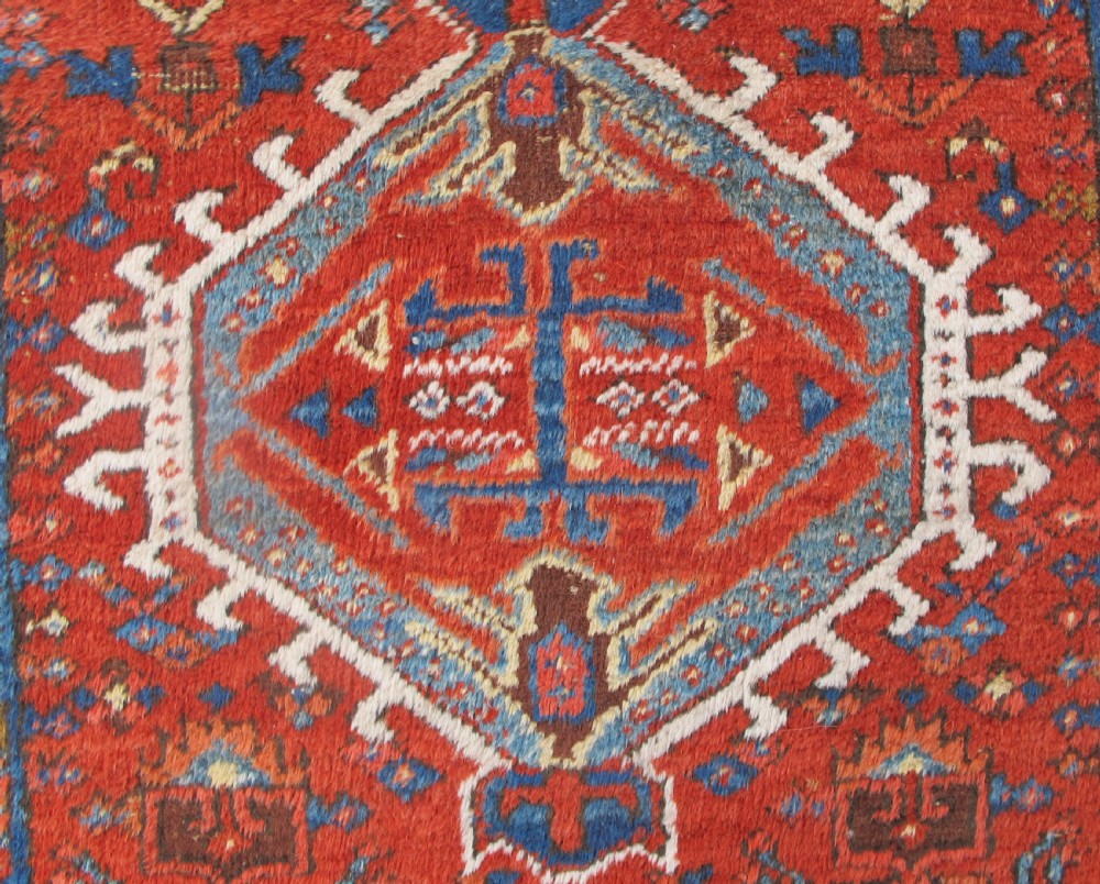 A long hand-knotted Persian Heriz wool runner rug featuring geometric medallions in shades of red, blue, and gold against a red field. View III