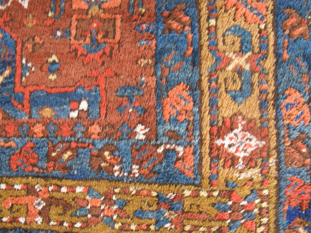 A long hand-knotted Persian Heriz wool runner rug featuring geometric medallions in shades of red, blue, and gold against a red field. View V