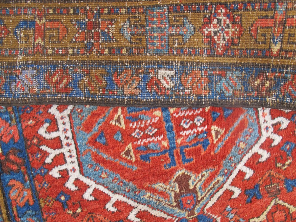 A long hand-knotted Persian Heriz wool runner rug featuring geometric medallions in shades of red, blue, and gold against a red field. View VII