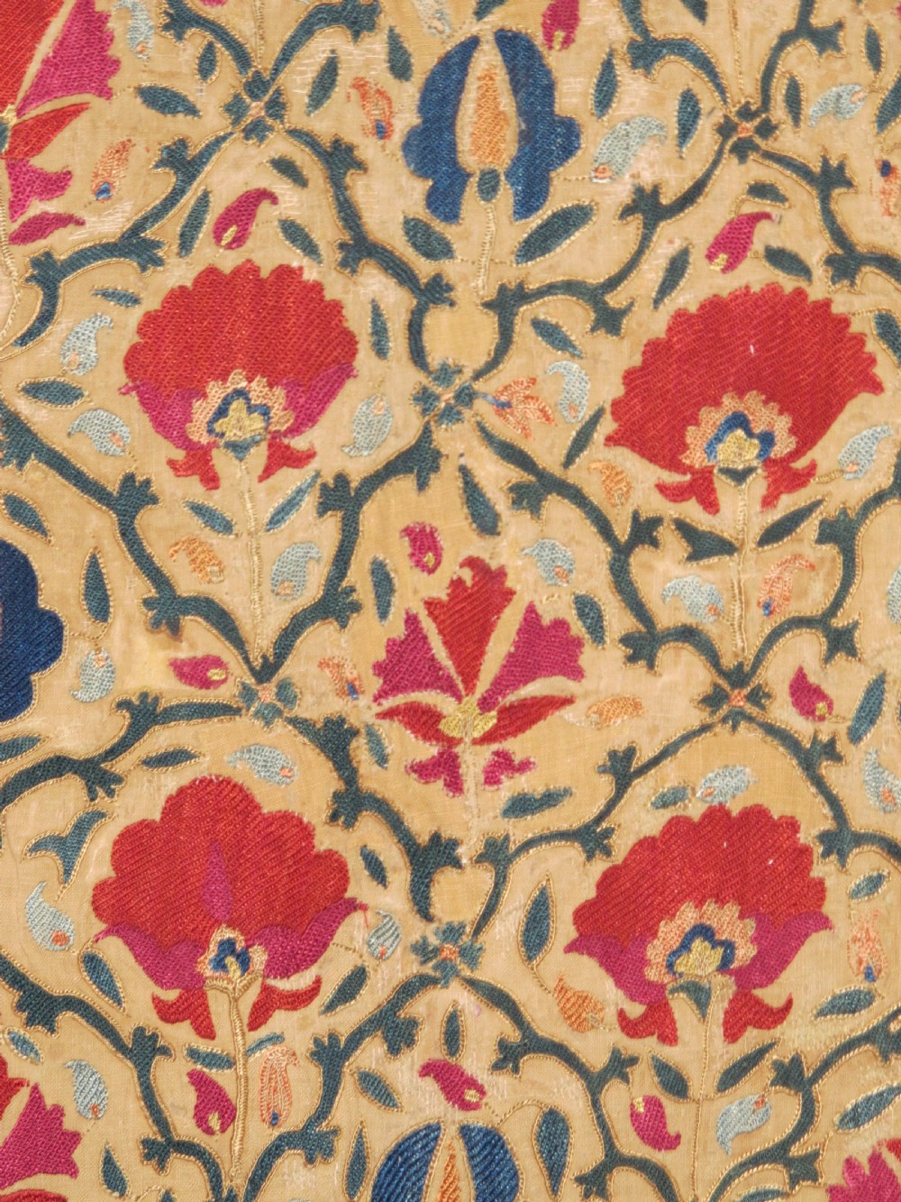 A 19th-century Bokhara suzani textile featuring red silk floral embroidery on a cream cotton ground surrounded by a wide rosette border. View IV