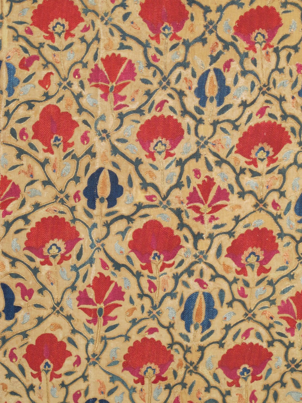 A 19th-century Bokhara suzani textile featuring red silk floral embroidery on a cream cotton ground surrounded by a wide rosette border. View V