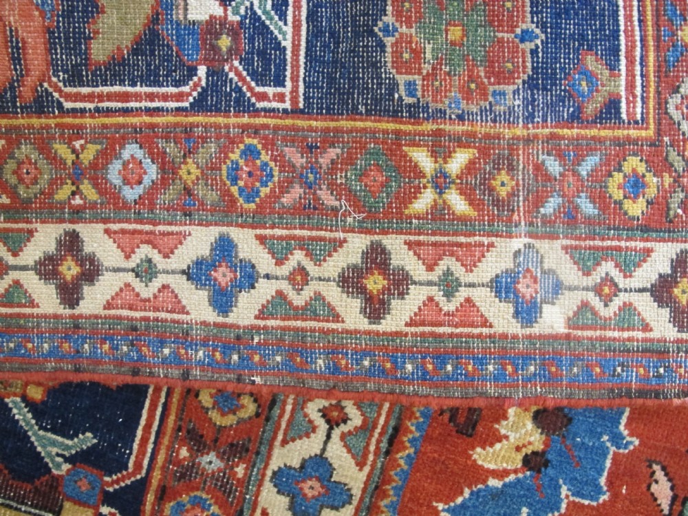A large hand-knotted Persian Sultanabad wool carpet featuring a red central field filled with floral motifs and bordered by a wide navy band. View V