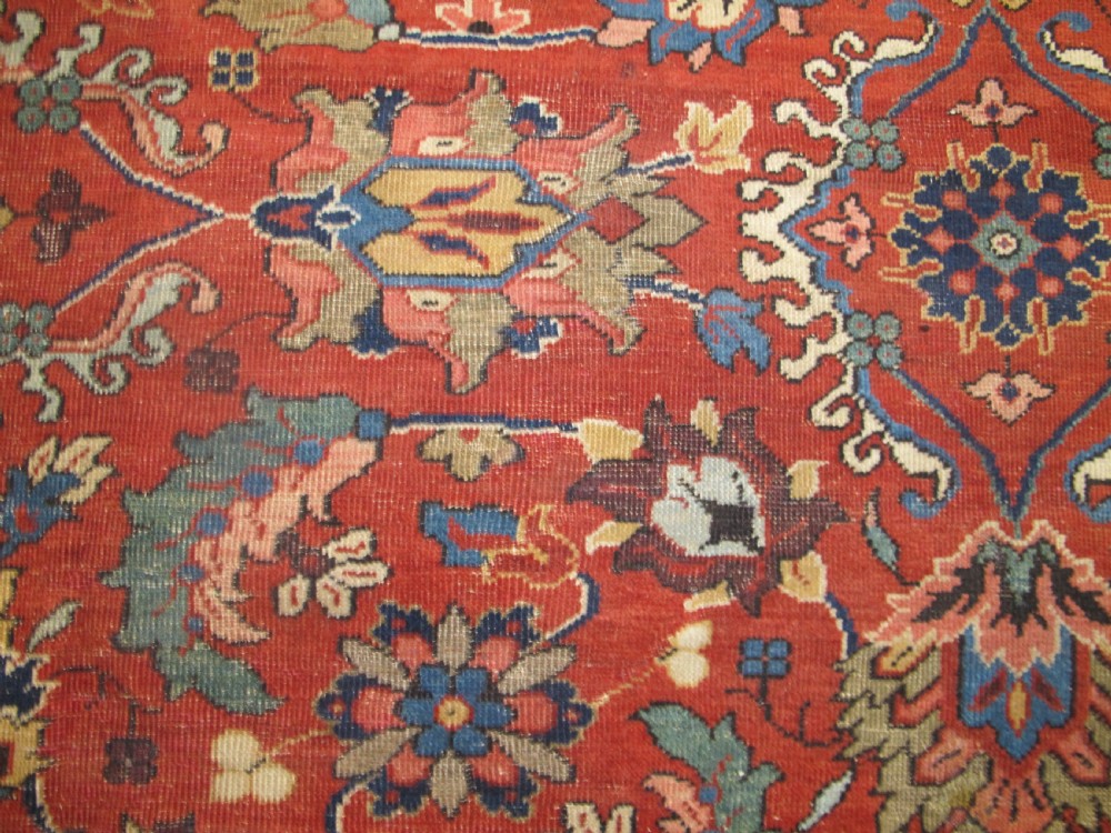 A large hand-knotted Persian Sultanabad wool carpet featuring a red central field filled with floral motifs and bordered by a wide navy band. View VI