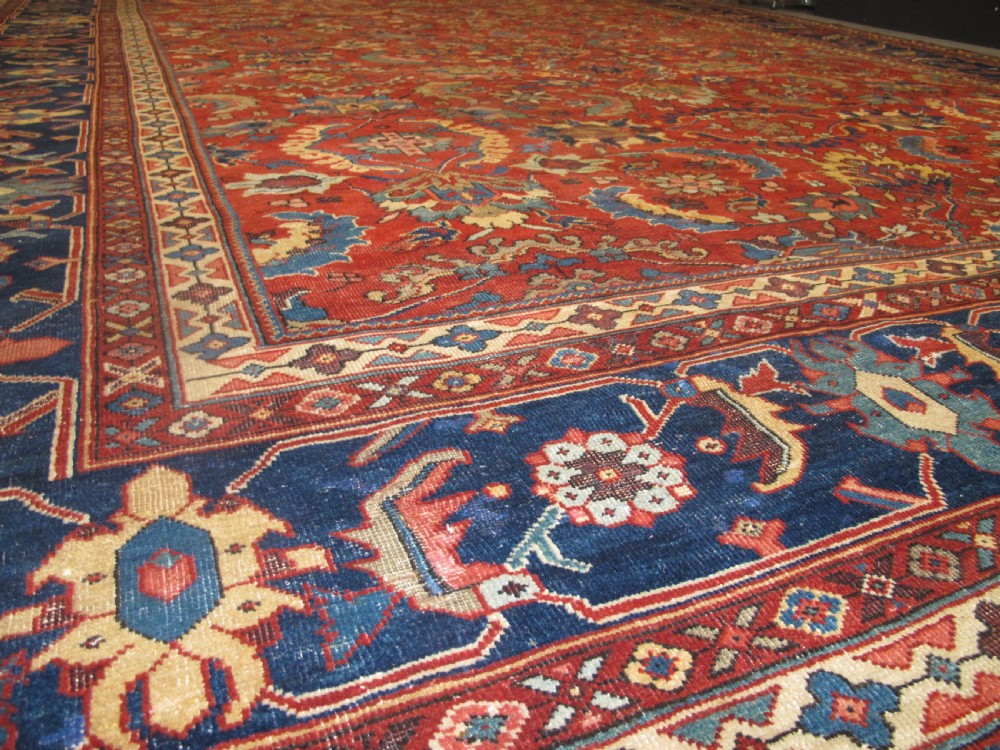 A large hand-knotted Persian Sultanabad wool carpet featuring a red central field filled with floral motifs and bordered by a wide navy band. View VII