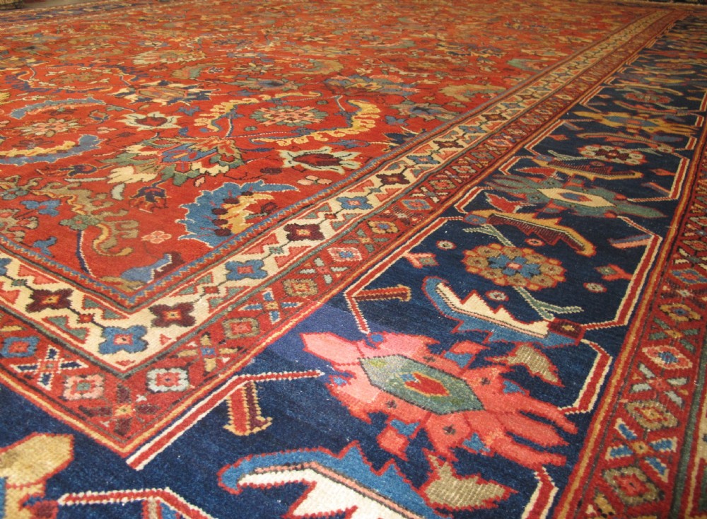 A large hand-knotted Persian Sultanabad wool carpet featuring a red central field filled with floral motifs and bordered by a wide navy band. View VIII