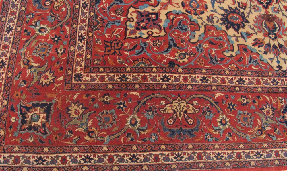 A large hand-knotted Persian Isfahan carpet featuring a central dark blue and red medallion on an ivory ground with a wide crimson floral border. View II