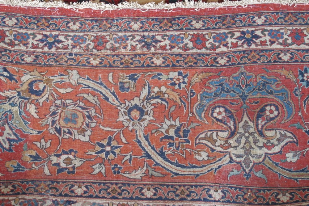 A large hand-knotted Persian Isfahan carpet featuring a central dark blue and red medallion on an ivory ground with a wide crimson floral border. View V