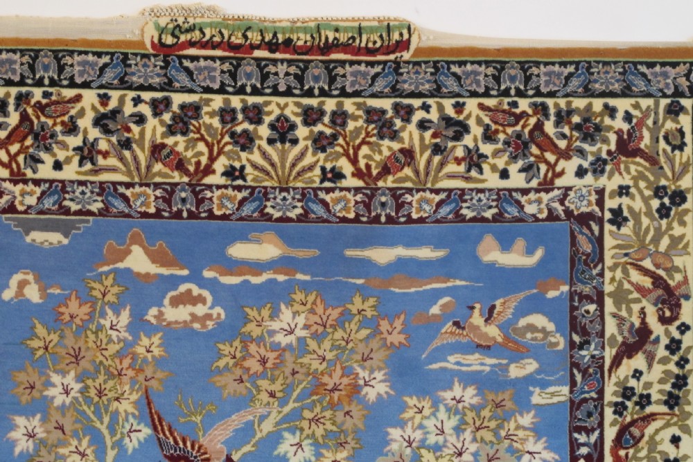 A hand-knotted Persian pictorial rug displaying figures seated beneath a blossoming tree on a sky blue field, framed by an ornate floral border. View IV