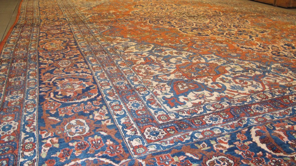 A large hand-knotted Persian Isfahan wool rug featuring a elaborate central medallion with indigo and cream arabesque floral patterns on a deep red field. View VIII