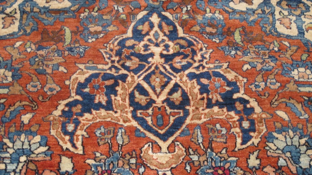A large hand-knotted Persian Isfahan wool rug featuring a elaborate central medallion with indigo and cream arabesque floral patterns on a deep red field. View IX