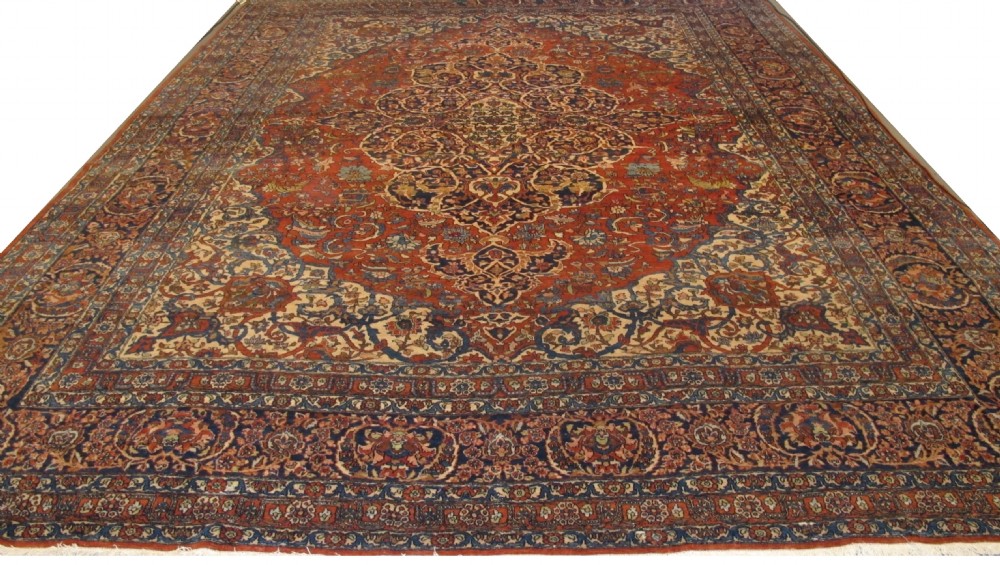 A large hand-knotted Persian Isfahan wool rug featuring a elaborate central medallion with indigo and cream arabesque floral patterns on a deep red field. View X