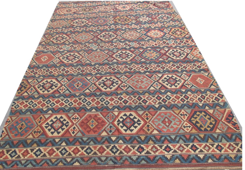 An antique 19th-century flat-woven Caucasian kilim rug featuring horizontal bands filled with geometric diamond and hexagon patterns in terracotta, indigo, ochre, and cream.