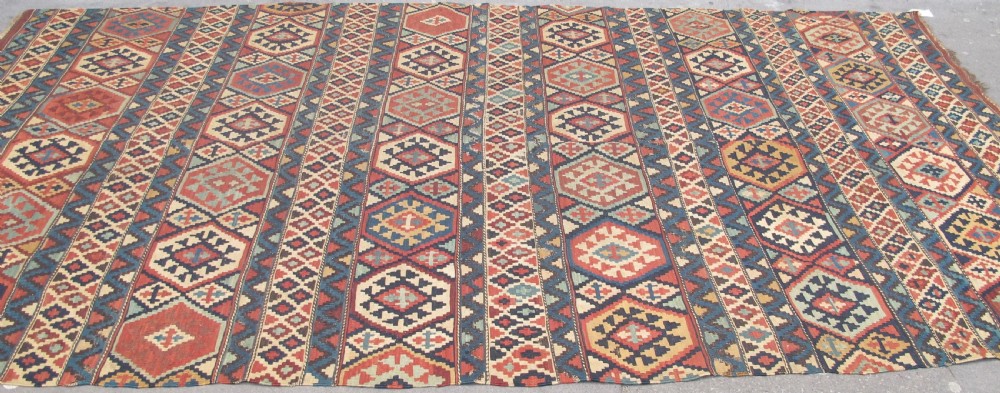 An antique 19th-century flat-woven Caucasian kilim rug featuring horizontal bands filled with geometric diamond and hexagon patterns in terracotta, indigo, ochre, and cream. View III