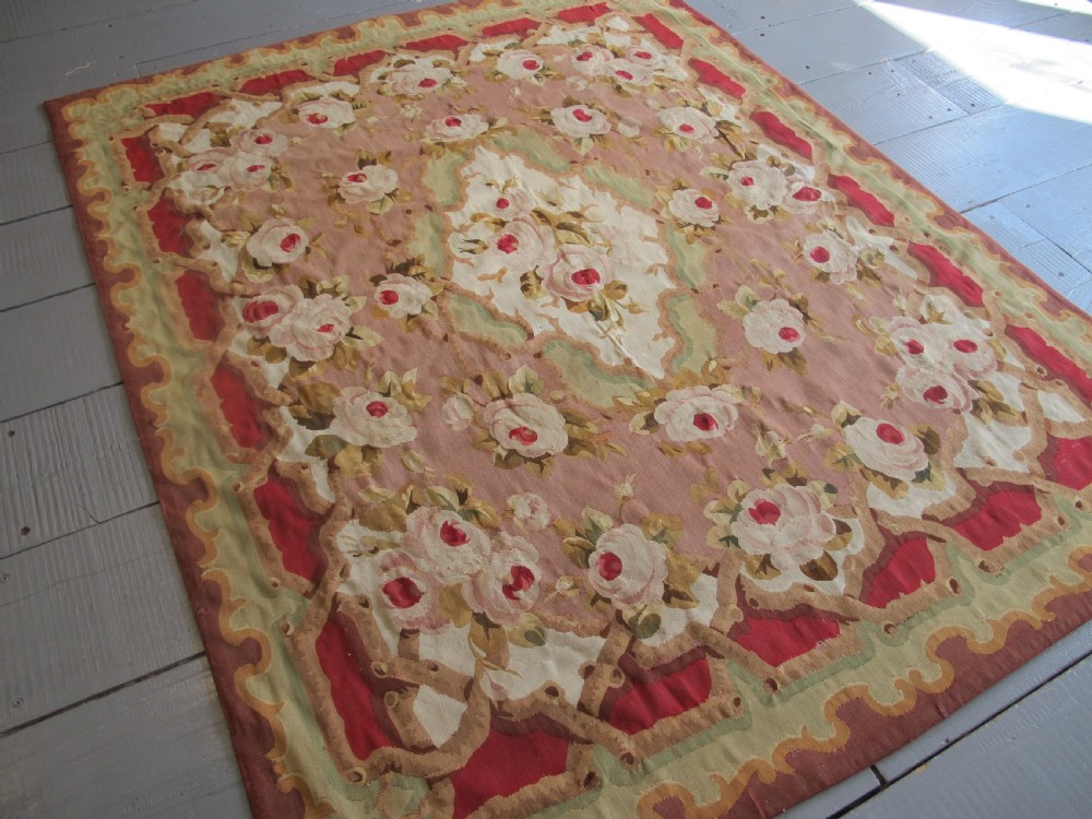 A rectangular antique French Aubusson flatweave wool rug featuring a central floral medallion surrounded by rose motifs, scrollwork borders, and shades of pink, red, green, and cream. View II