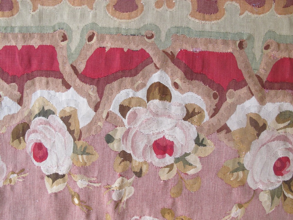 A rectangular antique French Aubusson flatweave wool rug featuring a central floral medallion surrounded by rose motifs, scrollwork borders, and shades of pink, red, green, and cream. View V