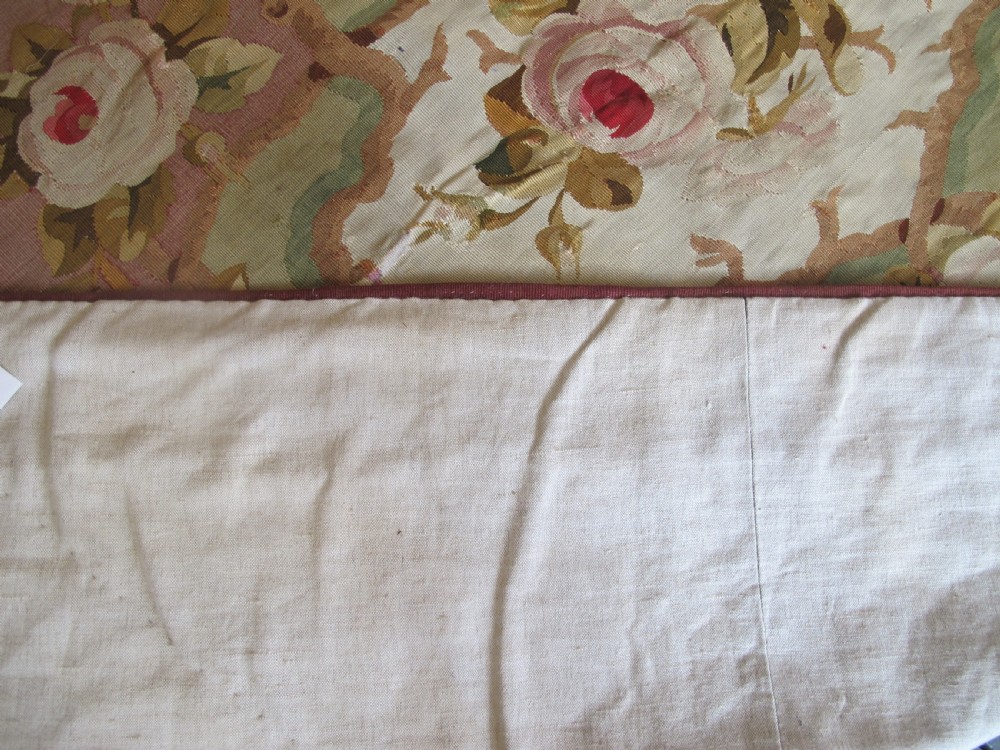 A rectangular antique French Aubusson flatweave wool rug featuring a central floral medallion surrounded by rose motifs, scrollwork borders, and shades of pink, red, green, and cream. View VI