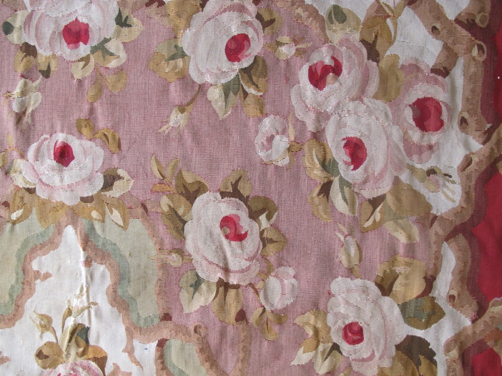 A rectangular antique French Aubusson flatweave wool rug featuring a central floral medallion surrounded by rose motifs, scrollwork borders, and shades of pink, red, green, and cream. View VII