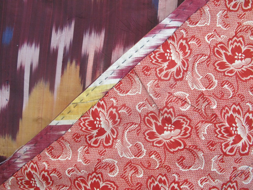A rectangular handwoven silk ikat textile panel displaying repeating floral and botanical motifs in shades of burgundy, magenta, pink, and ochre yellow. View VIII