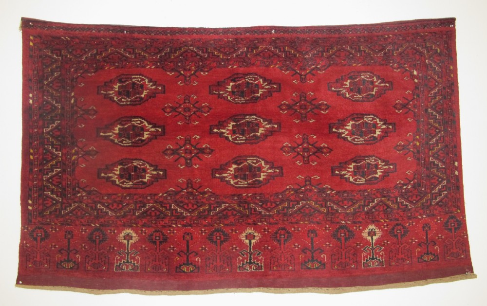 A rectangular hand-knotted red wool Ersari chuval featuring octagonal gol motifs, geometric borders, and a decorative lower panel.