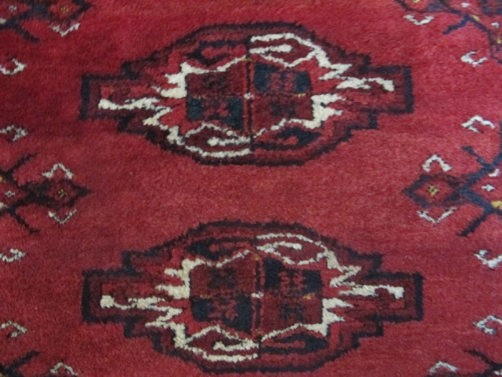 A rectangular hand-knotted red wool Ersari chuval featuring octagonal gol motifs, geometric borders, and a decorative lower panel. View III