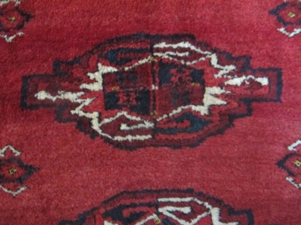 A rectangular hand-knotted red wool Ersari chuval featuring octagonal gol motifs, geometric borders, and a decorative lower panel. View IV