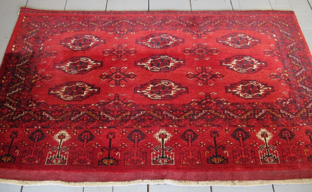 A rectangular hand-knotted red wool Ersari chuval featuring octagonal gol motifs, geometric borders, and a decorative lower panel. View V