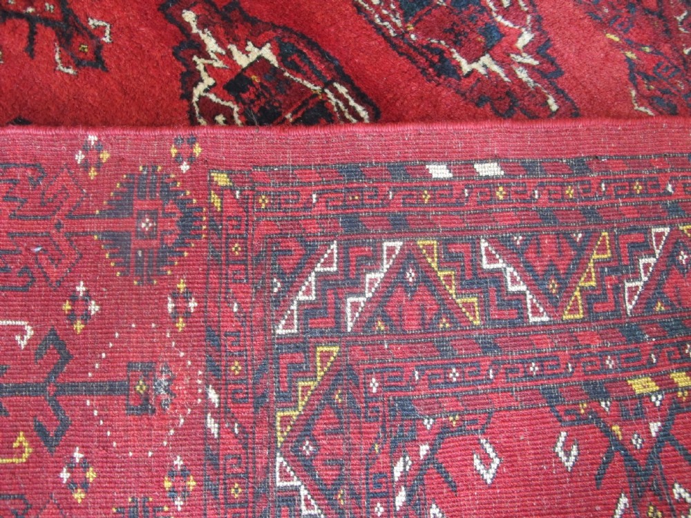 A rectangular hand-knotted red wool Ersari chuval featuring octagonal gol motifs, geometric borders, and a decorative lower panel. View VI