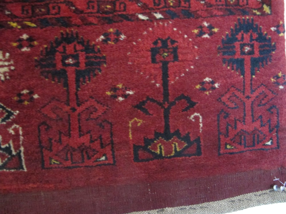 A rectangular hand-knotted red wool Ersari chuval featuring octagonal gol motifs, geometric borders, and a decorative lower panel. View VII