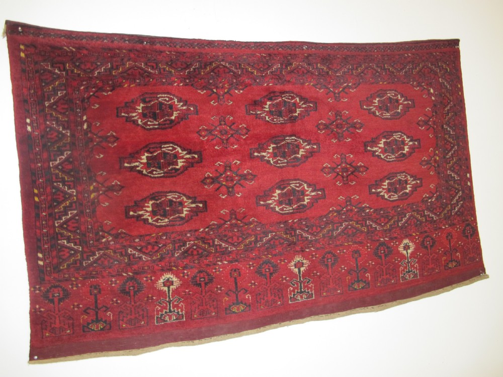 A rectangular hand-knotted red wool Ersari chuval featuring octagonal gol motifs, geometric borders, and a decorative lower panel. View X
