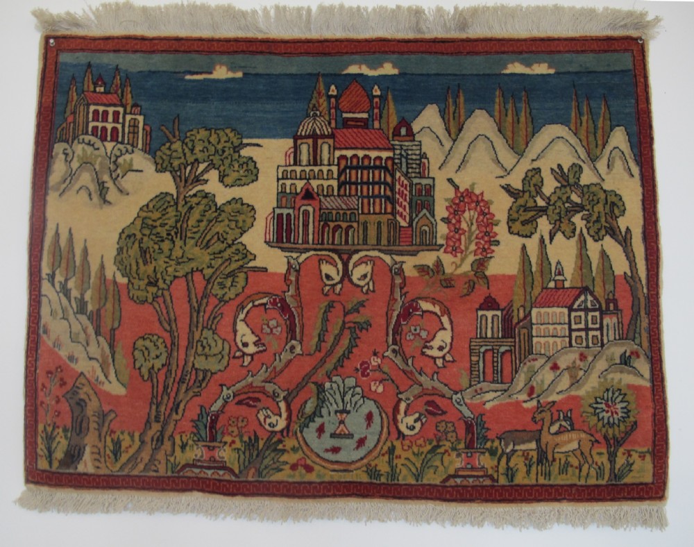 A pair of small Persian Kashan pictorial wool rugs featuring woven architectural scenes, trees, and animals set against terracotta red, cream, and navy blue backgrounds. View II