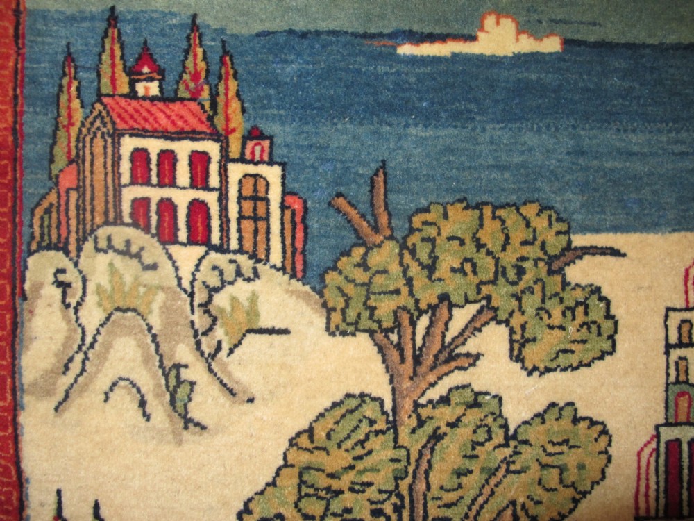 A pair of small Persian Kashan pictorial wool rugs featuring woven architectural scenes, trees, and animals set against terracotta red, cream, and navy blue backgrounds. View V