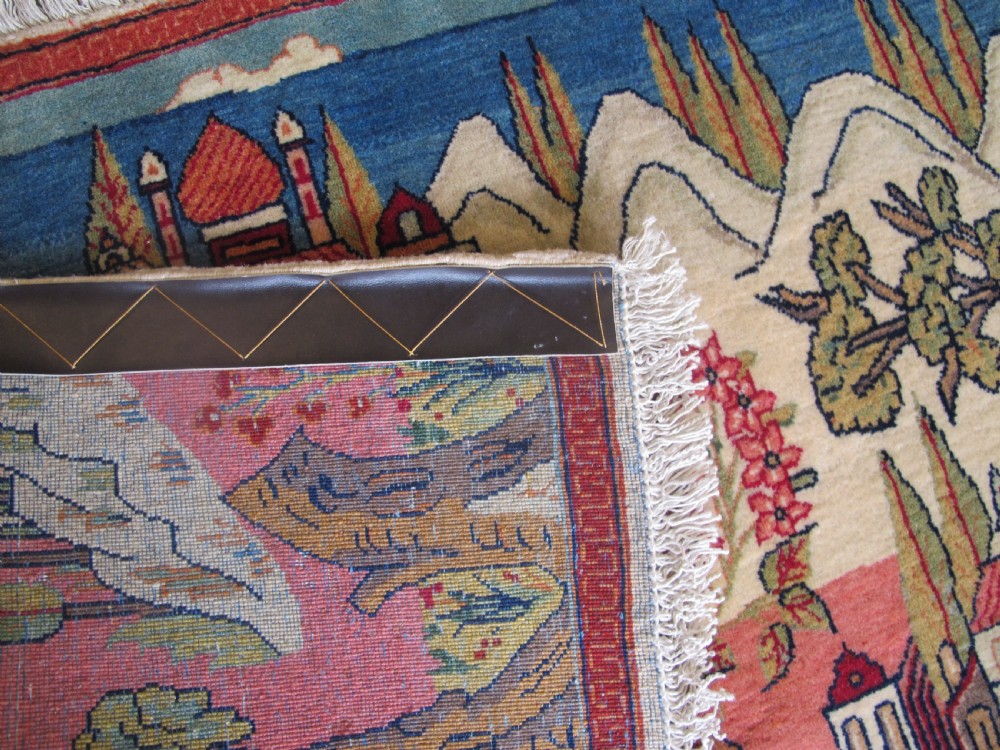 A pair of small Persian Kashan pictorial wool rugs featuring woven architectural scenes, trees, and animals set against terracotta red, cream, and navy blue backgrounds. View IX