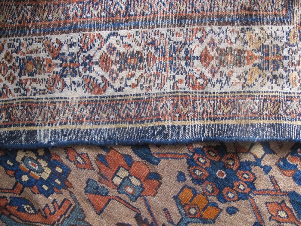An antique hand-knotted Hamadan carpet featuring intricate geometric and floral patterns in terracotta, indigo blue, and tan hues. View VII