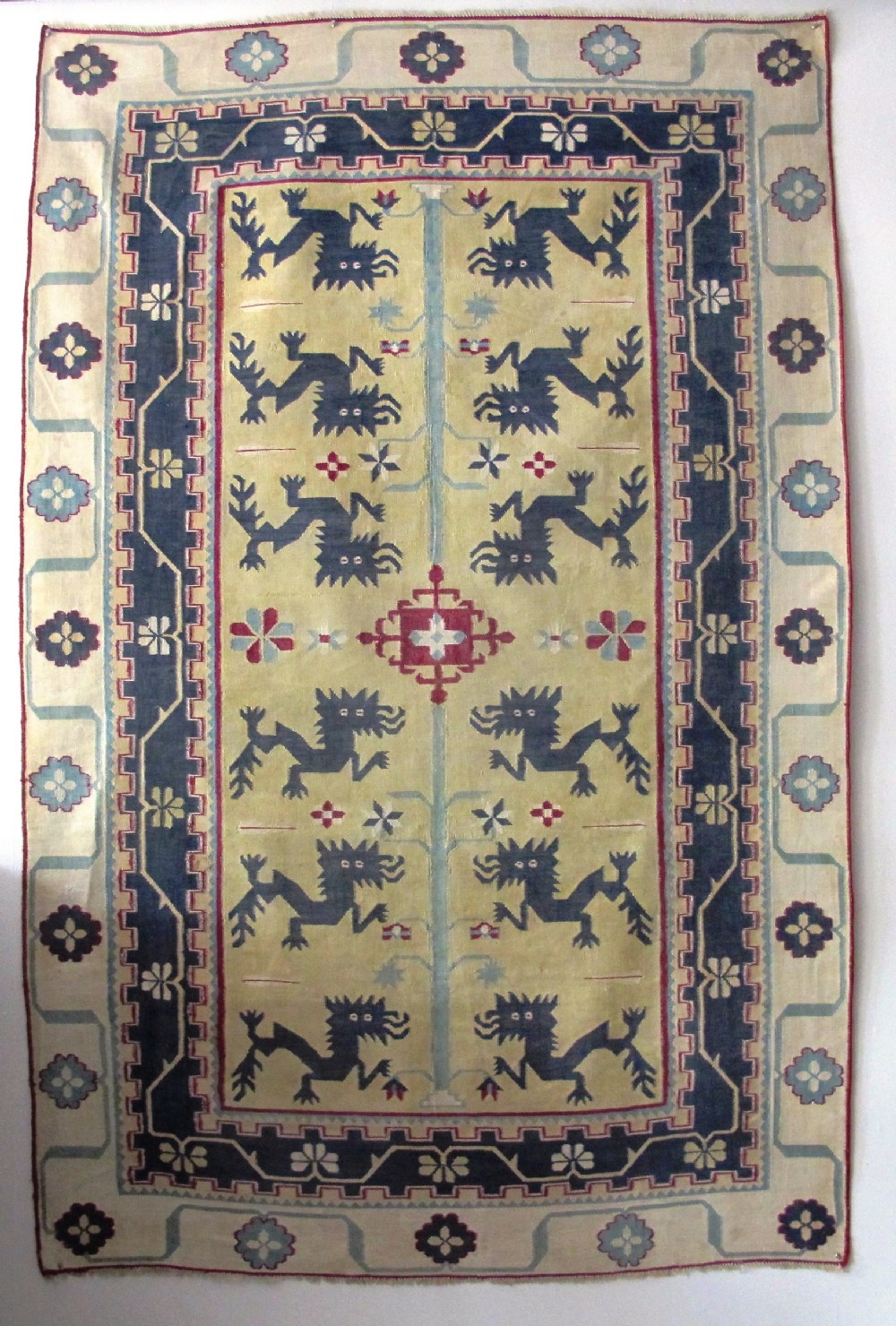 An antique Indian flatweave cotton dhurrie rug featuring blue stylised creature motifs on a pale yellow field surrounded by geometric patterned borders.