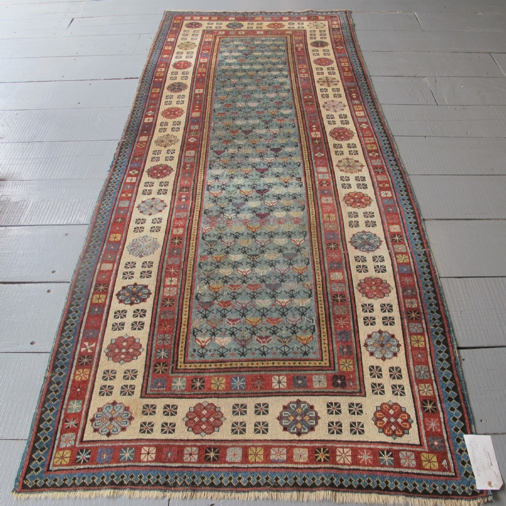 An antique Caucasian Talish hand-knotted wool long rug featuring a light blue central field with geometric motifs bordered by ivory and red patterned bands.
