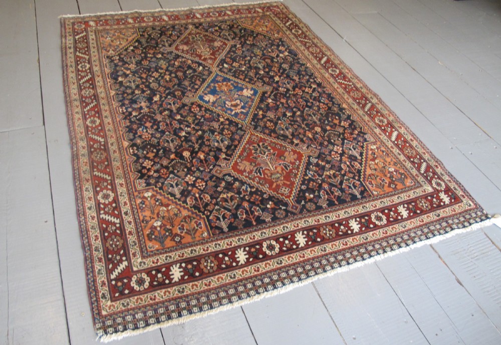 A hand-knotted Persian Qashqai wool rug featuring a dark navy field with central diamond medallions, geometric floral motifs, and a multi-tiered decorative border. View II