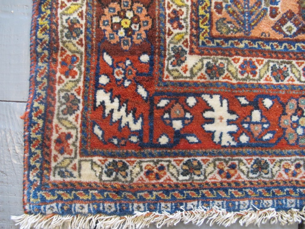 A hand-knotted Persian Qashqai wool rug featuring a dark navy field with central diamond medallions, geometric floral motifs, and a multi-tiered decorative border. View IX