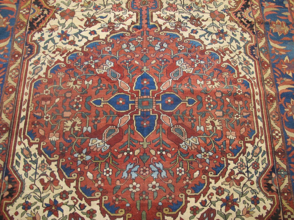 A late 19th-century hand-knotted Persian Melayir wool carpet featuring a large central terracotta medallion on a cream field framed by navy spandrels and a blue botanical border. View III