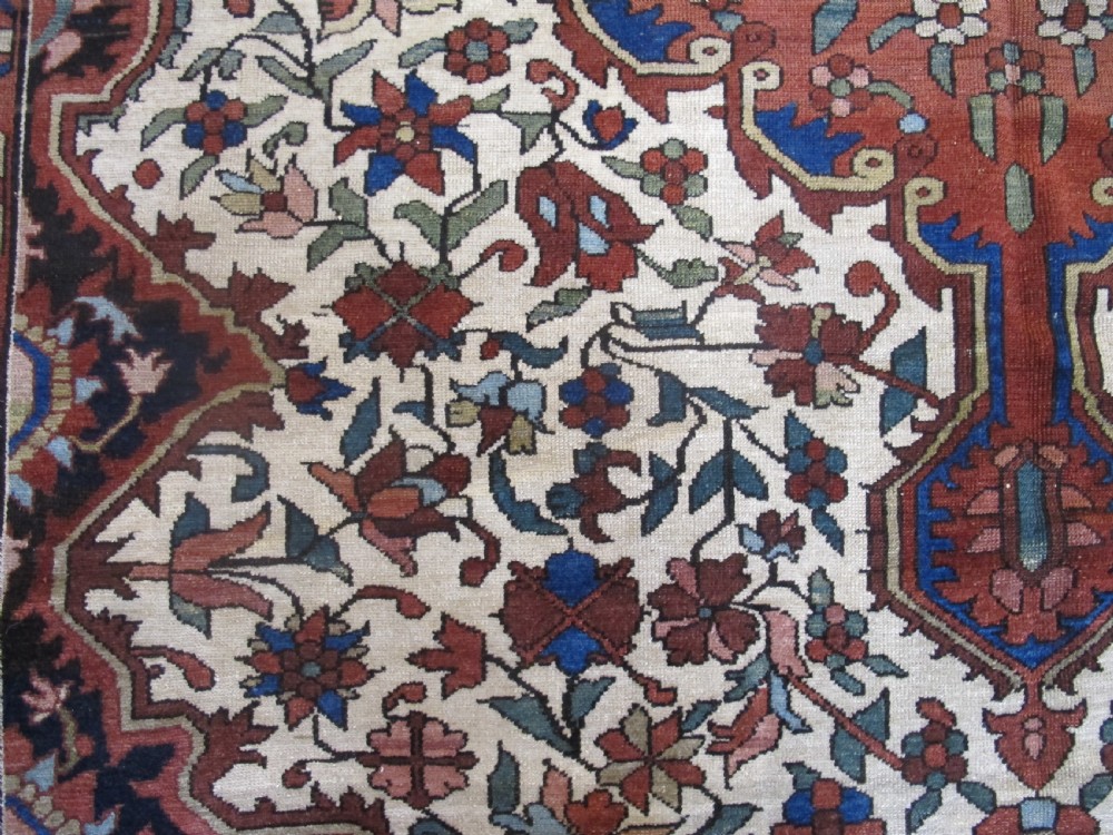 A late 19th-century hand-knotted Persian Melayir wool carpet featuring a large central terracotta medallion on a cream field framed by navy spandrels and a blue botanical border. View IV