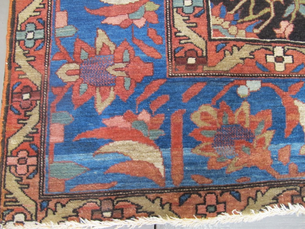 A late 19th-century hand-knotted Persian Melayir wool carpet featuring a large central terracotta medallion on a cream field framed by navy spandrels and a blue botanical border. View V