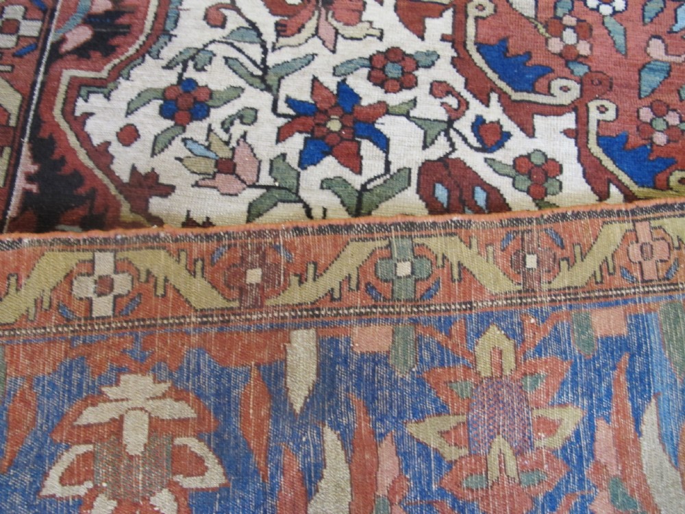 A late 19th-century hand-knotted Persian Melayir wool carpet featuring a large central terracotta medallion on a cream field framed by navy spandrels and a blue botanical border. View VII