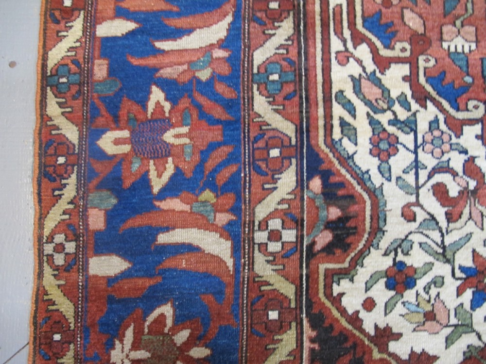 A late 19th-century hand-knotted Persian Melayir wool carpet featuring a large central terracotta medallion on a cream field framed by navy spandrels and a blue botanical border. View VIII