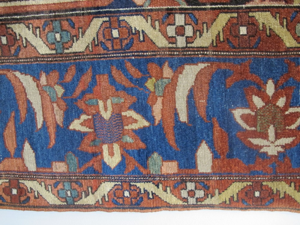 A late 19th-century hand-knotted Persian Melayir wool carpet featuring a large central terracotta medallion on a cream field framed by navy spandrels and a blue botanical border. View XI