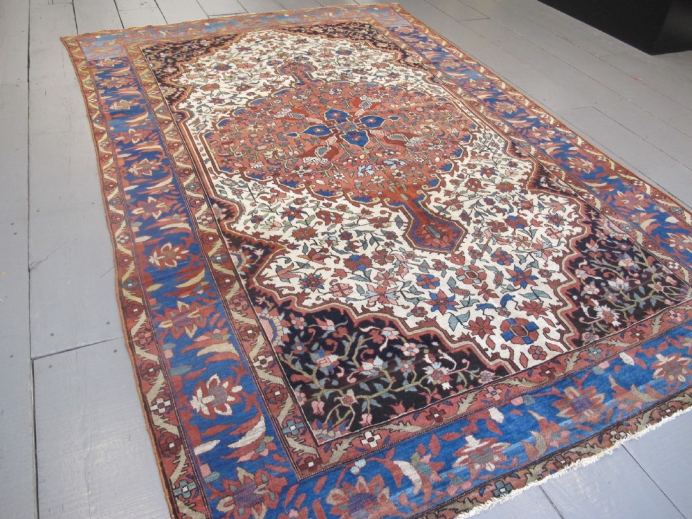 A late 19th-century hand-knotted Persian Melayir wool carpet featuring a large central terracotta medallion on a cream field framed by navy spandrels and a blue botanical border. View XIII