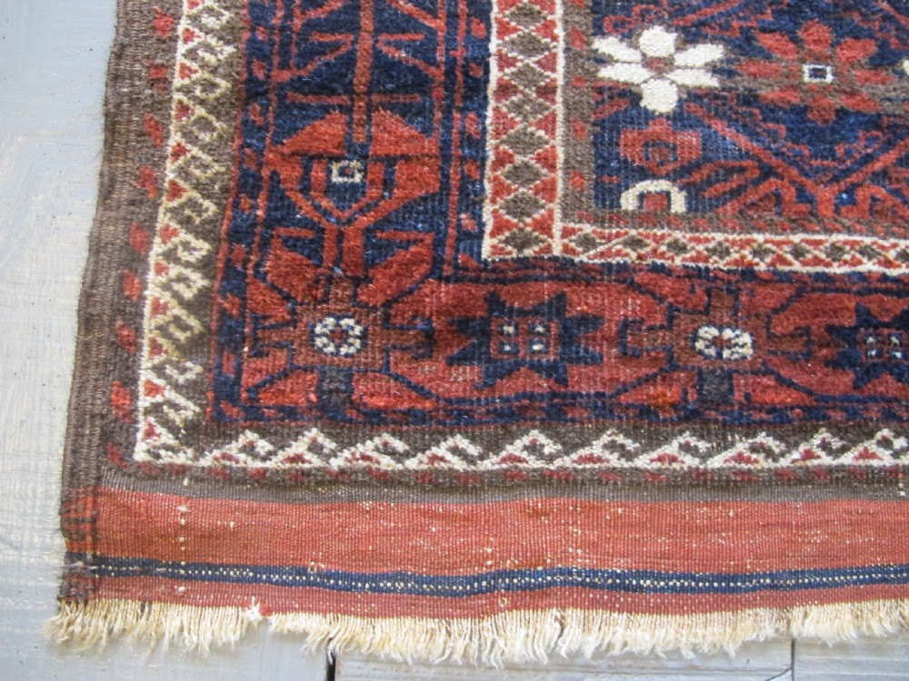 An antique Balouchi handwoven wool runner rug displaying repeating geometric star motifs in deep red, navy, and ivory tones on a dark background. View IV
