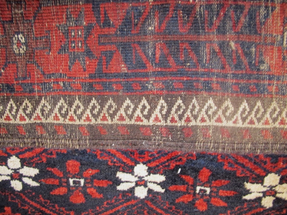 An antique Balouchi handwoven wool runner rug displaying repeating geometric star motifs in deep red, navy, and ivory tones on a dark background. View VIII