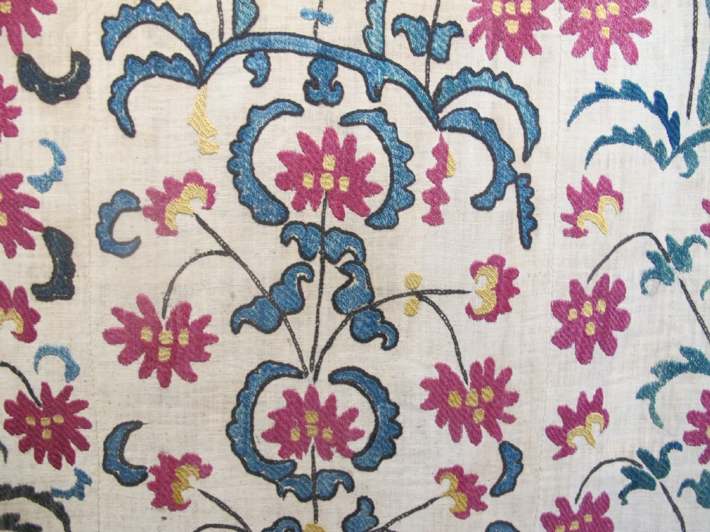 A large rectangular Central Asian suzani textile featuring repeating vertical columns of red embroidered floral motifs on a natural beige cotton substrate. View III