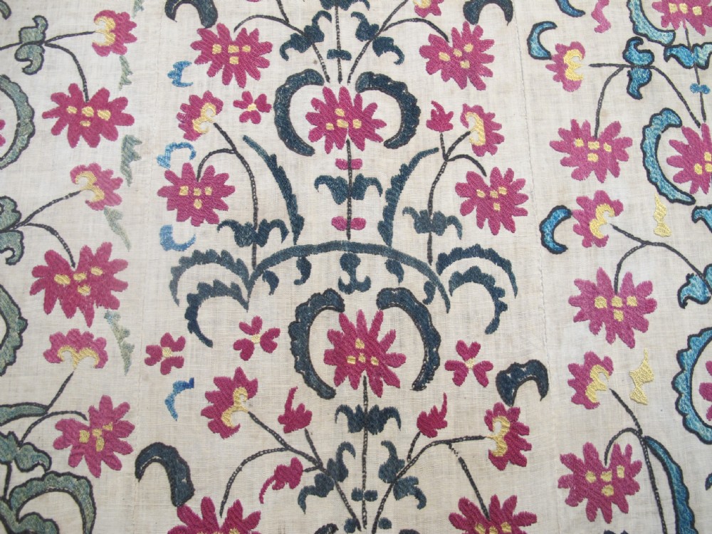 A large rectangular Central Asian suzani textile featuring repeating vertical columns of red embroidered floral motifs on a natural beige cotton substrate. View VI