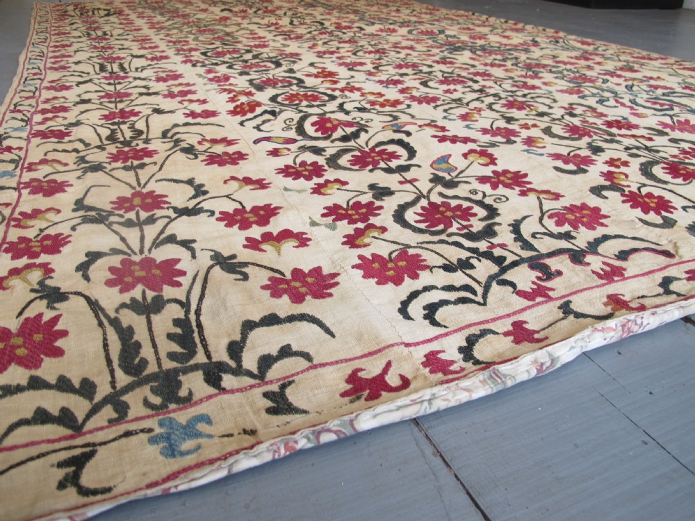 A large rectangular Central Asian suzani textile featuring repeating vertical columns of red embroidered floral motifs on a natural beige cotton substrate. View VIII