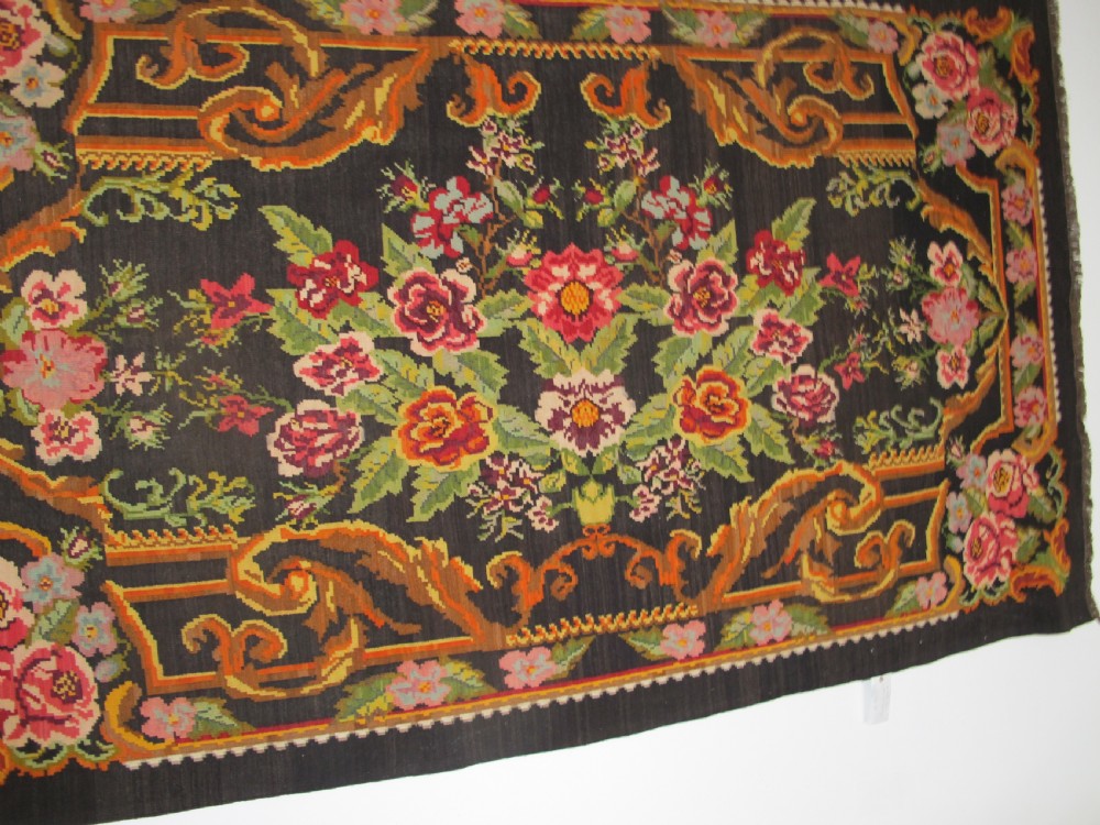 A large rectangular handwoven flatweave rug featuring vibrant floral bouquets and scrollwork borders on a dark black field. View VIII